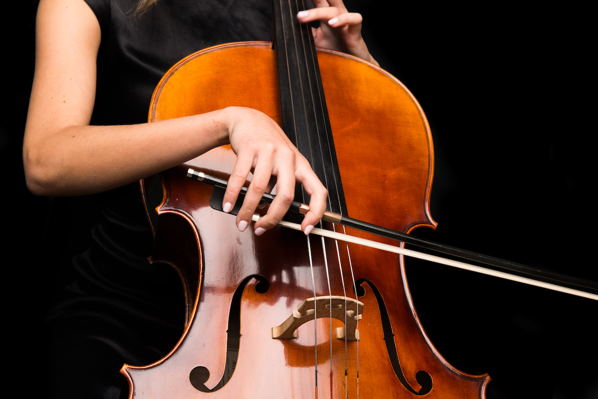 Young girl playing the cello on isolated black background